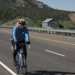 A cyclist rides on a highway in Santa Barbara, surrounded by impressive mountains under a clear sky.