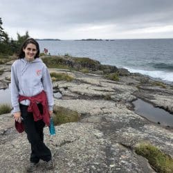 Woman stands on rocks on Lake Superior shore