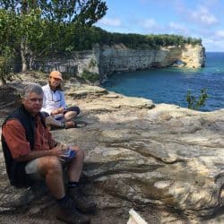 Two hikers sit on a cliff overlooking Lake Superior in Isle Royale National Park