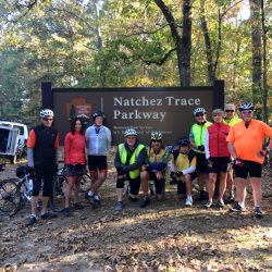 A group of cyclists pose in front of the official sign for the Natchez Trace Parkway near Nashville, Tennessee