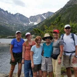 A happy group of hikers pose in front of Mills Lake in Rocky Mountain National Park