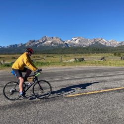 A cyclist rides our of Stanley, Idaho with the Sawtooth Mountains as his backdrop