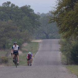 A pair of cyclists enjoy a ride down a peaceful country road in the beautiful Texas Hill Country.