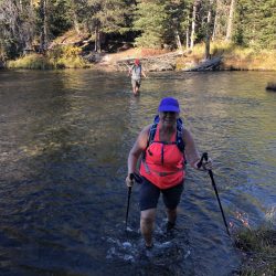 hiker hiking through a river in Yellowstone