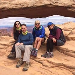 People sitting in front of a rock arch