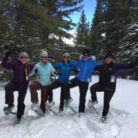 A group of friends show off their snowshoe prowess imid the deep snow in the woods of Rocky Mountain National Park